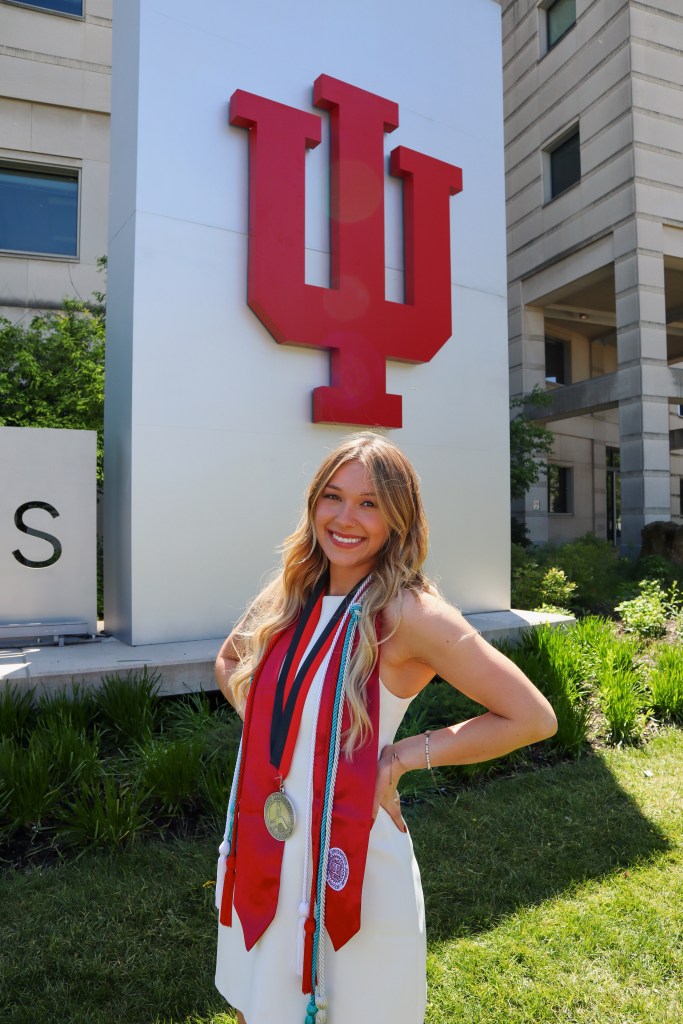 Alexia posing in front of the IU sign in her cords + medal
